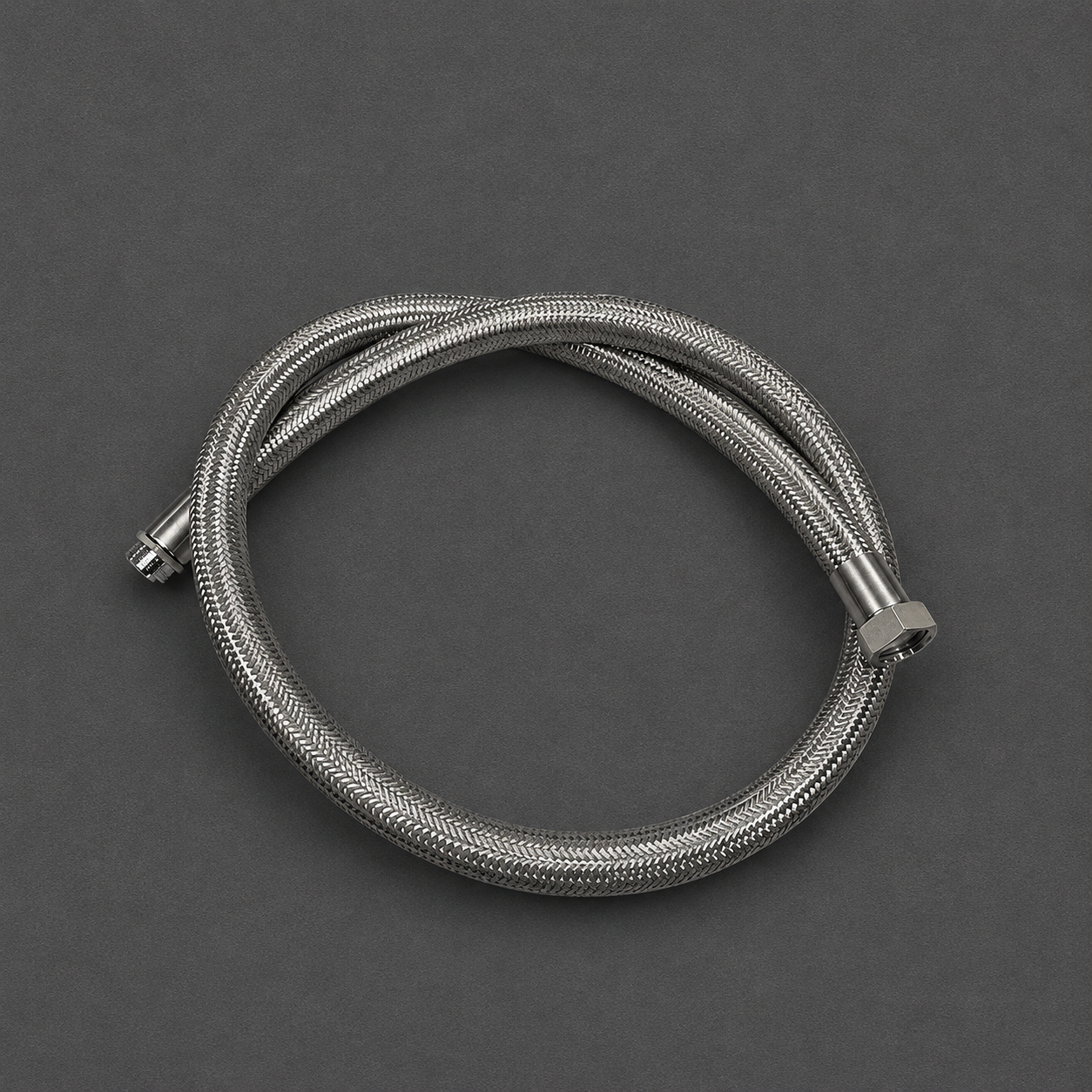 A coiled stainless steel braided hose with metal fittings, photographed on a dark gray background.