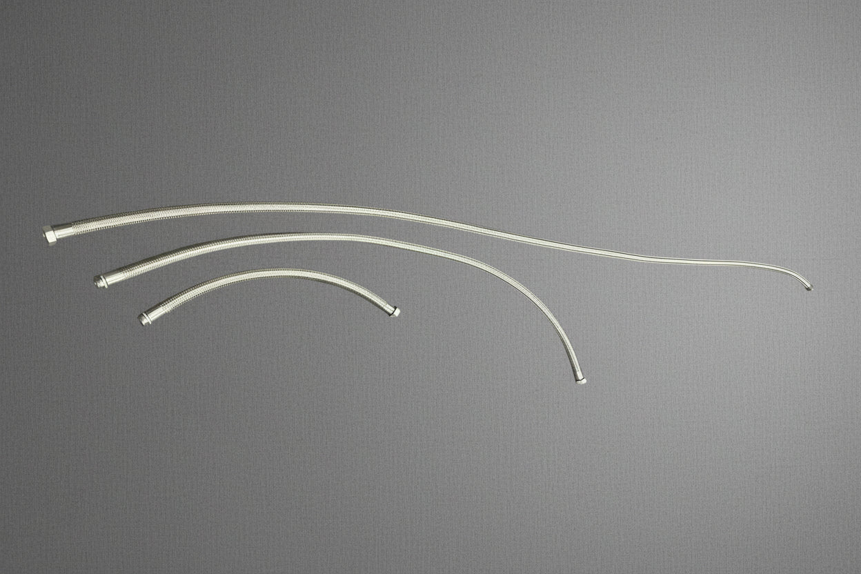 Three curved stainless steel braided hoses of varying lengths laid out on a gray mat