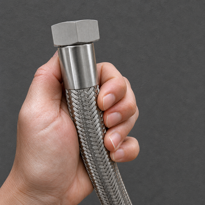 A close-up of a hand holding a stainless steel braided hose with a hexagonal metal connector against a dark gray background.